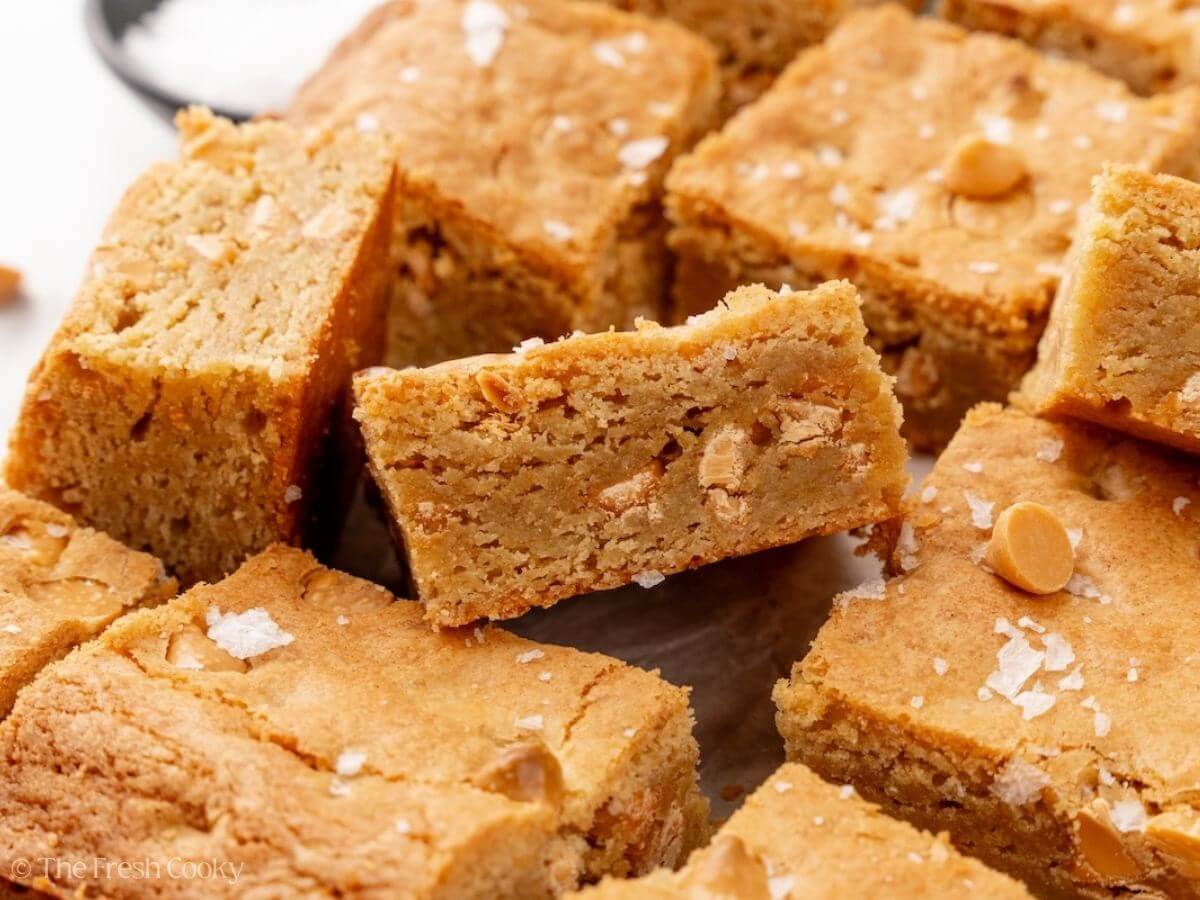 A bunch of squares of blondies with one poking up showing it's gooey middle.