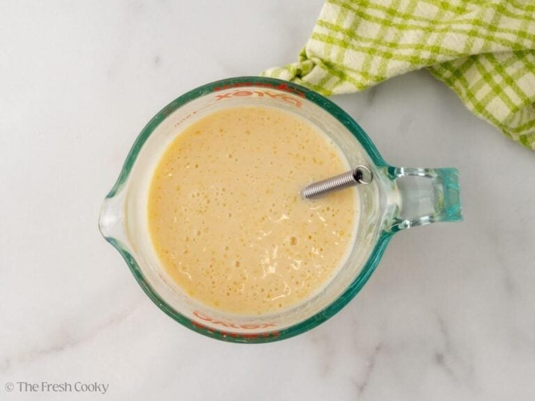 A glass measuring cup with liquid ingredients measured.