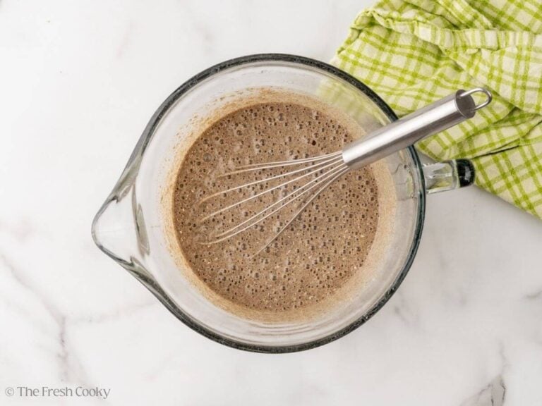 A large glass measuring cup with a whisk and mixed buckwheat pancake batter.