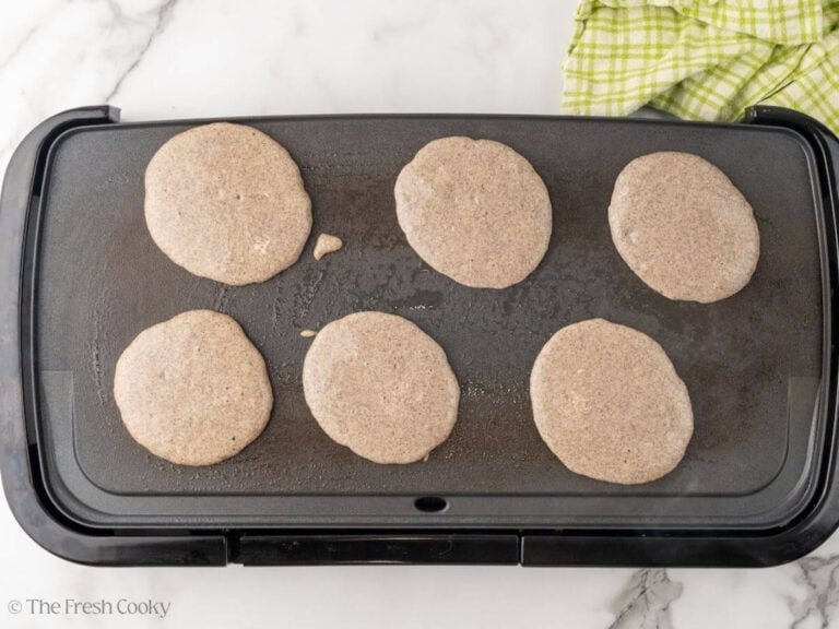 A griddle with buckwheat pancakes cooking.