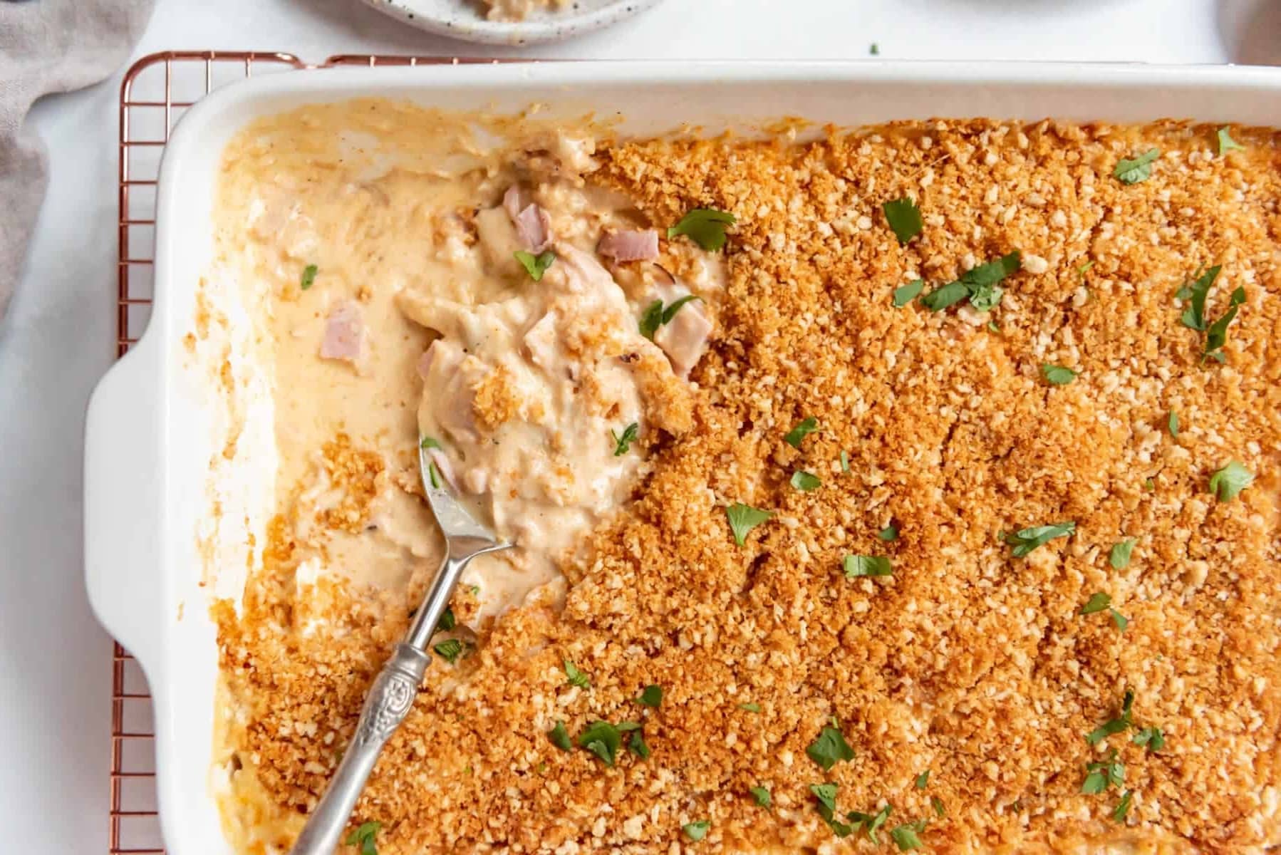 Chicken Cordon Bleu Casserole with leftover ham, in a casserole dish with a spoon serving.