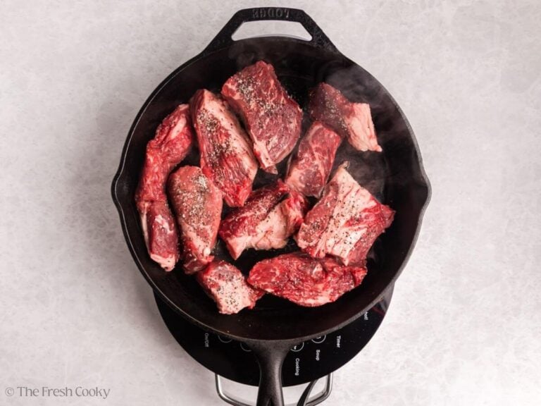 Searing the pieces of chuck roast in a skillet.