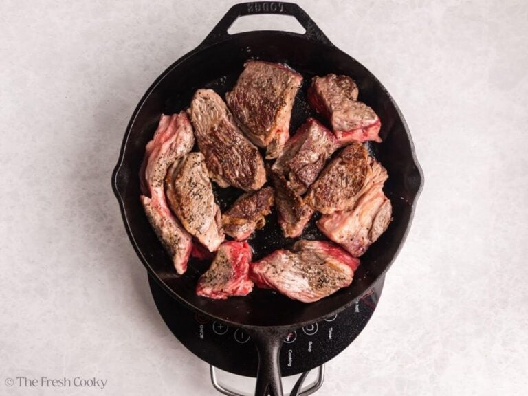 Chuck roast seared and flipped to the other side in a skillet.