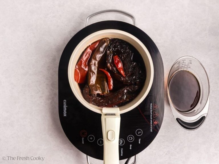 Dried chiles being rehydrated in a saucepan with beef broth.