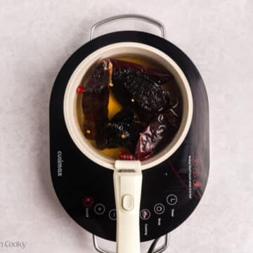 Rehydrated chiles in beef broth in a saucepan.