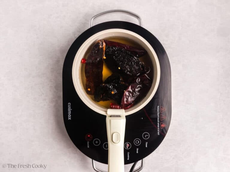 Rehydrated chiles in beef broth in a saucepan.