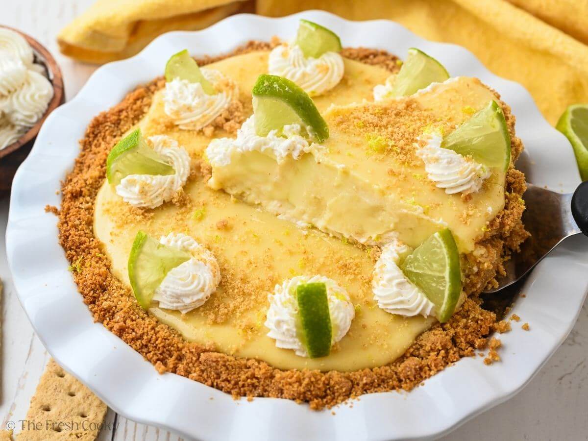 Key lime pie with a spatula lifting out a wedge of pie.