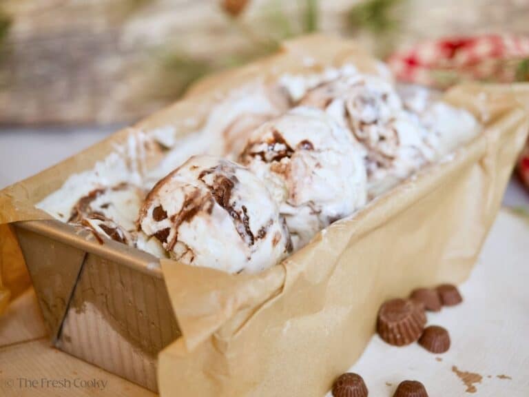Moose tracks ice cream in a loaf pan with three scoops on top.