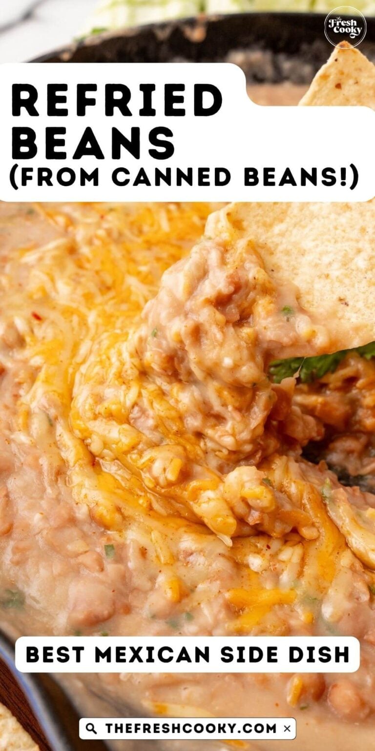 A tortilla chip being scooped into refried beans topped with cheese, for pinning.