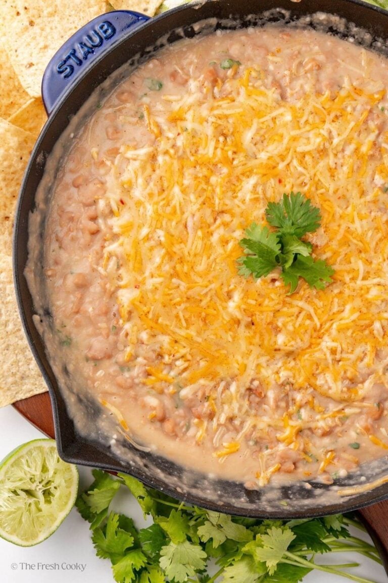 Refried beans in a skillet topped with cheese and cilantro.