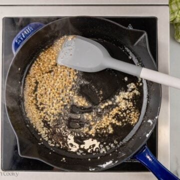 Garlic and spices cooking in the lard in a skillet.