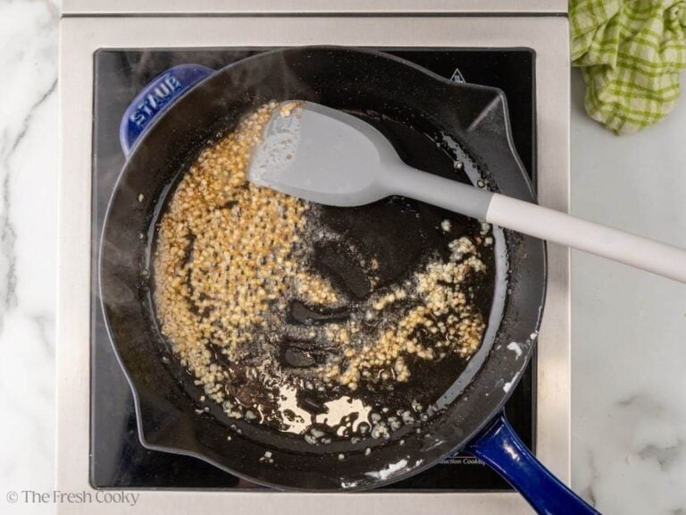 Garlic and spices cooking in the lard in a skillet.