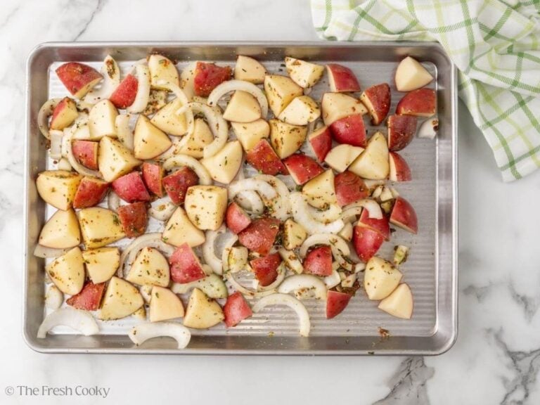 A sheet pan with red potatoes and onions spread out.