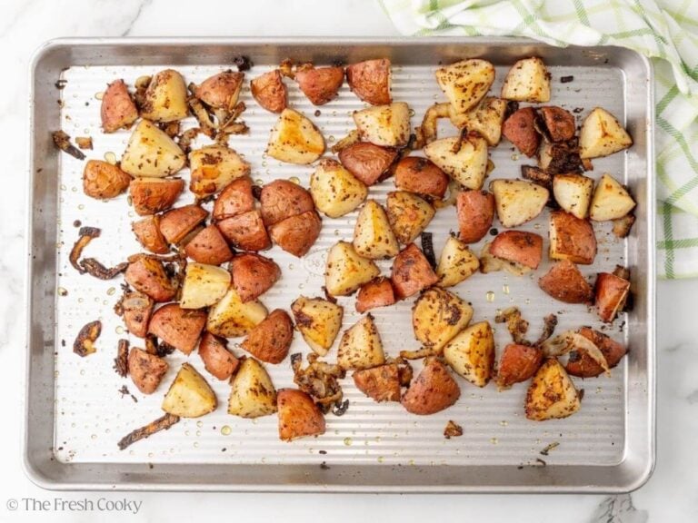 A sheet pan with roasted potatoes with onions.