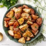 Overhead image of a green bowl with roasted potatoes with onions.