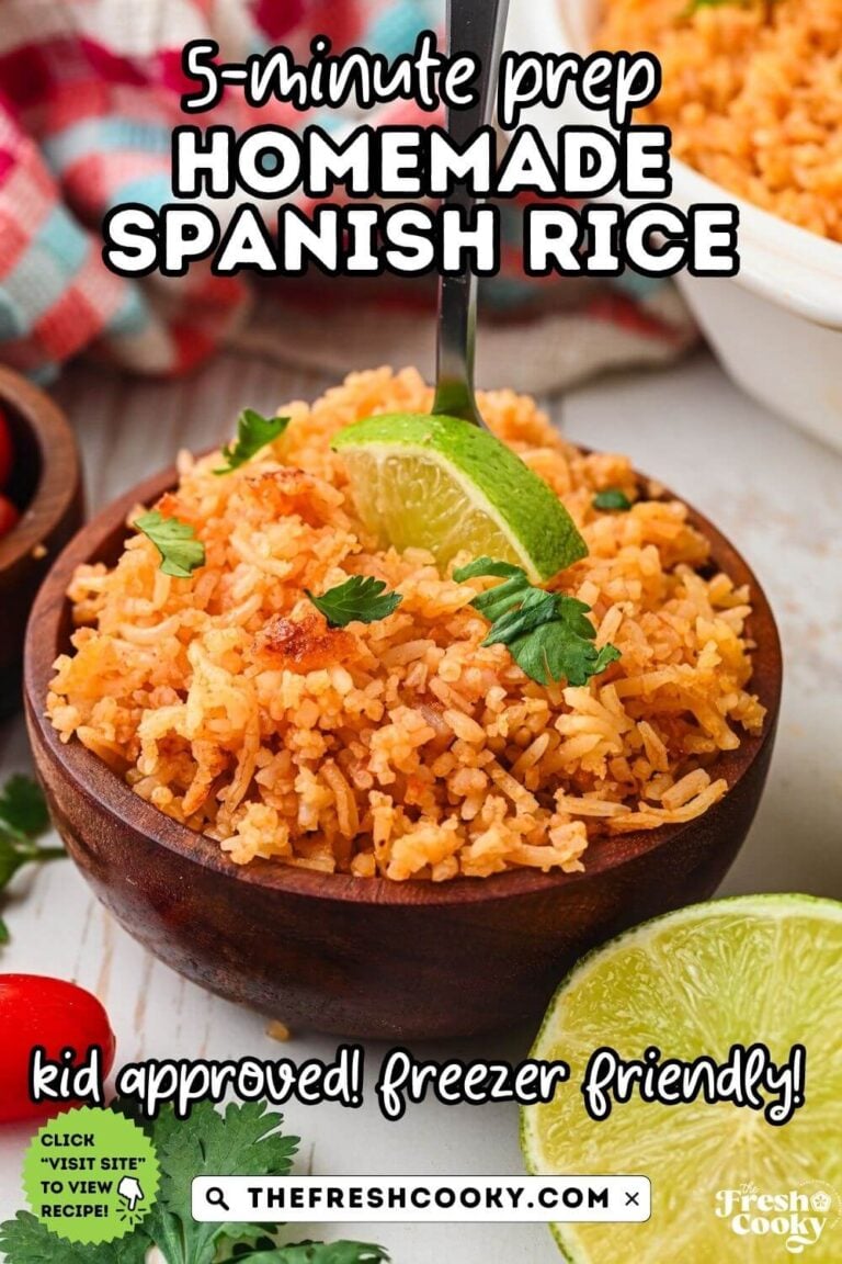 A wooden bowl filled with orange-ish red Mexican rice, garnished with a piece of lime and chopped cilantro, for pinning.