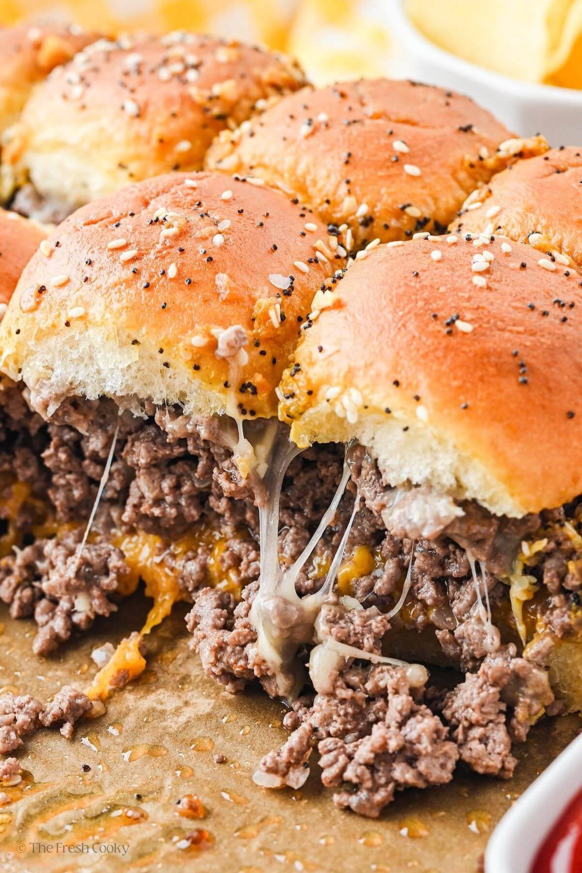 Close up of pan of cheeseburgery sliders with gooey, stringy cheese and loaded with ground beef.