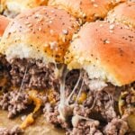 Close-up of stringy, gooey and cheesey, cheeseburger sliders in a pan.