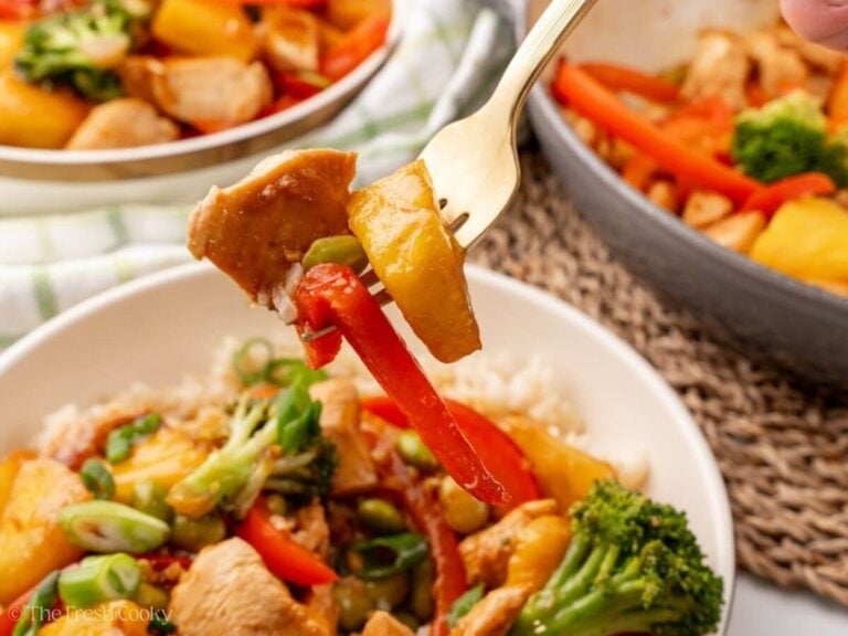 Fork with chicken teriyaki on it hovering over a bowl.
