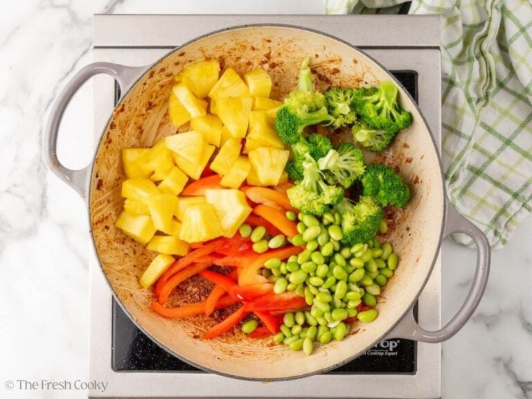 Pineapple, broccoli, edamame, and bell peppers added to skillet to sear.