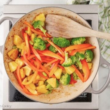 Seared vegetables and pineapple in a skillet.