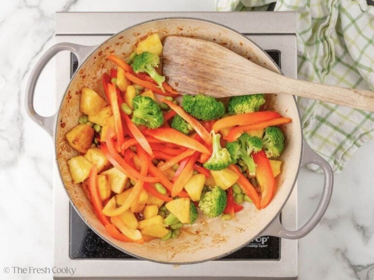 Seared vegetables and pineapple in a skillet.