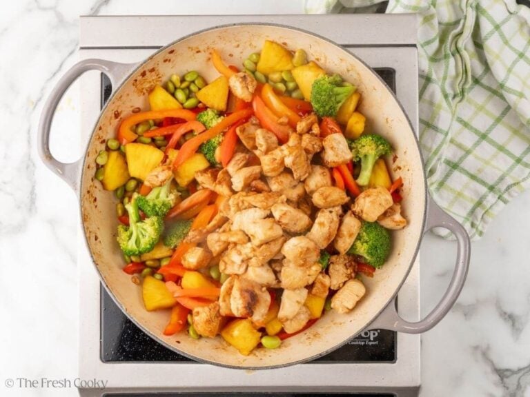 Teriyaki chicken added back to the vegetables mixture in a skillet.