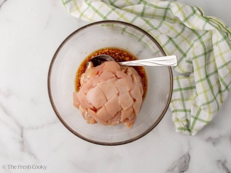 Diced chicken breast added to the chicken marinade in a bowl.