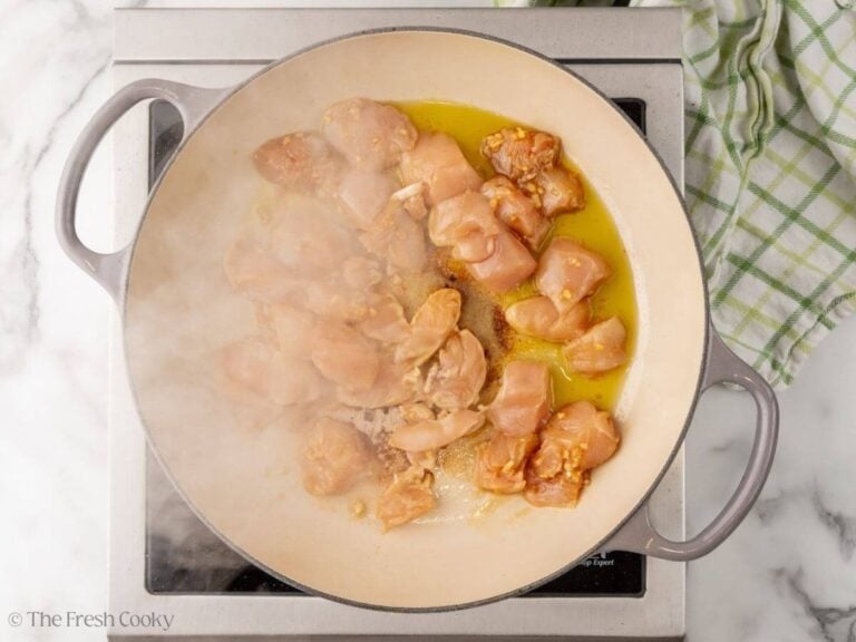 Searing the marinated chicken breast pieces in a skillet.