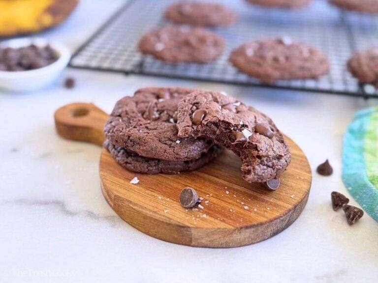 A couple of banana chocolate chip cookies on a wooden board, one with a bite taken out.