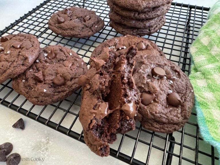Gooey chocolate banana cookies on a cooling rack, with a stack behind too.