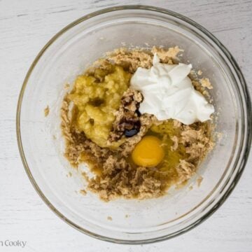 Eggs, banana, sour cream and vanilla added to the butter and sugar mixture in a bowl.