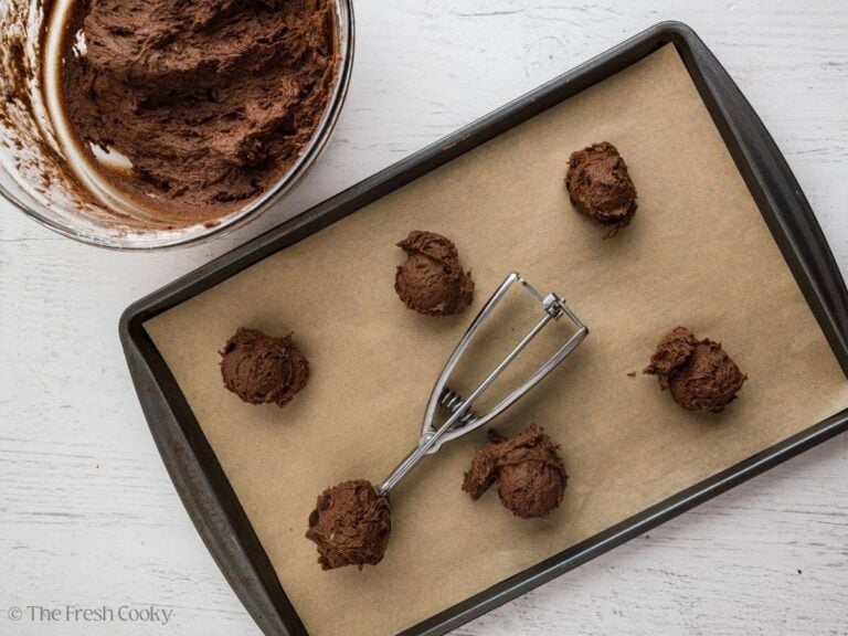 Scoops of chocolate banana cookie dough on a sheet pan.