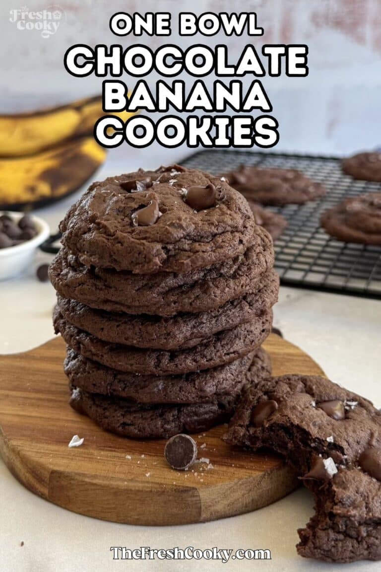 Chocolate banana cookies stacked on a wooden board, with a cookie with bite taken out. For pinning.