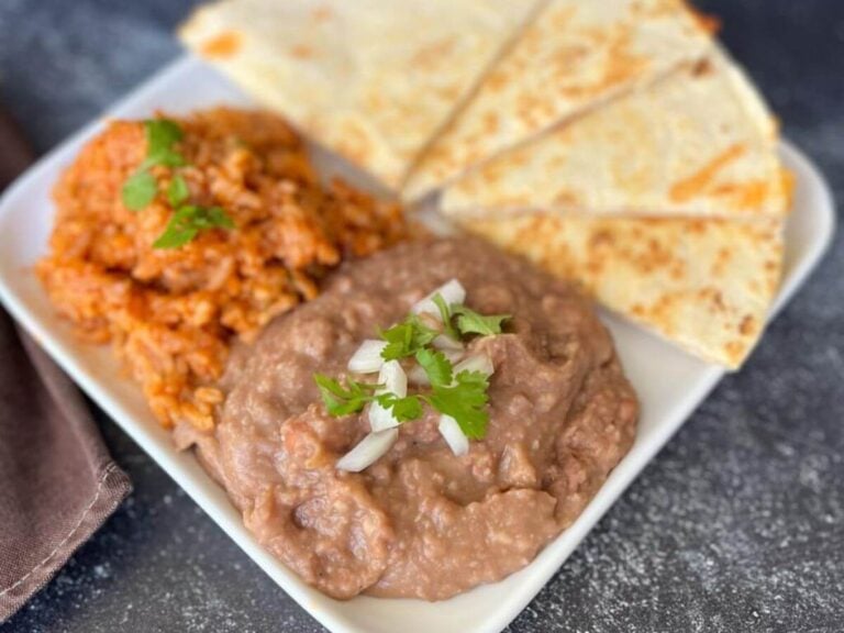 Refried beans, spanish rice on a plate with a quesadilla.