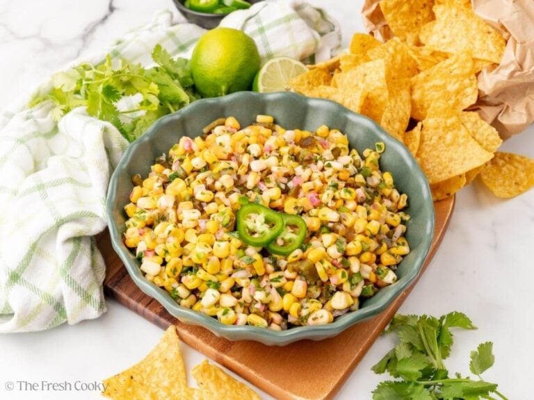Copycat chipotle corn salsa in a bowl garnished with jalapeno next to tortilla chips.