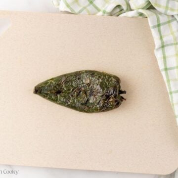 Roasted poblano pepper on a cutting board.