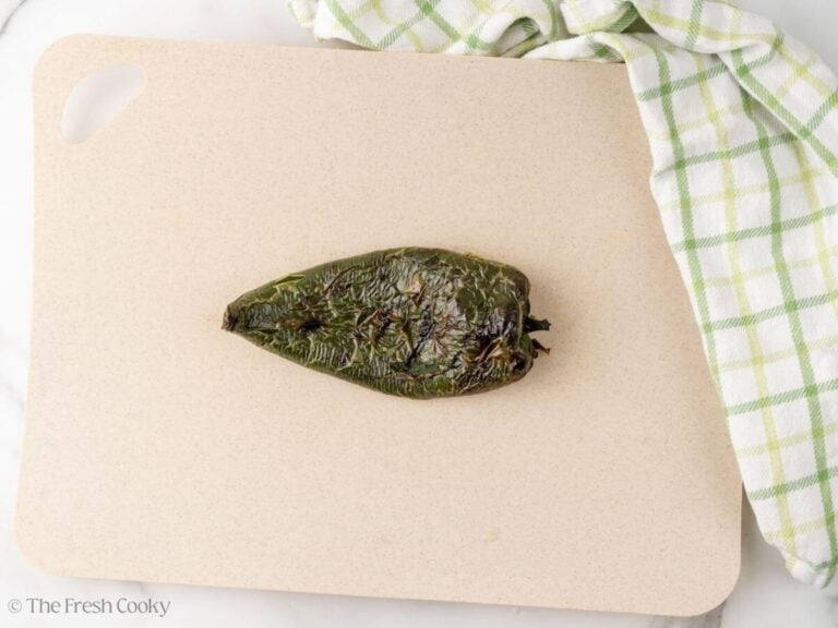 Roasted poblano pepper on a cutting board.