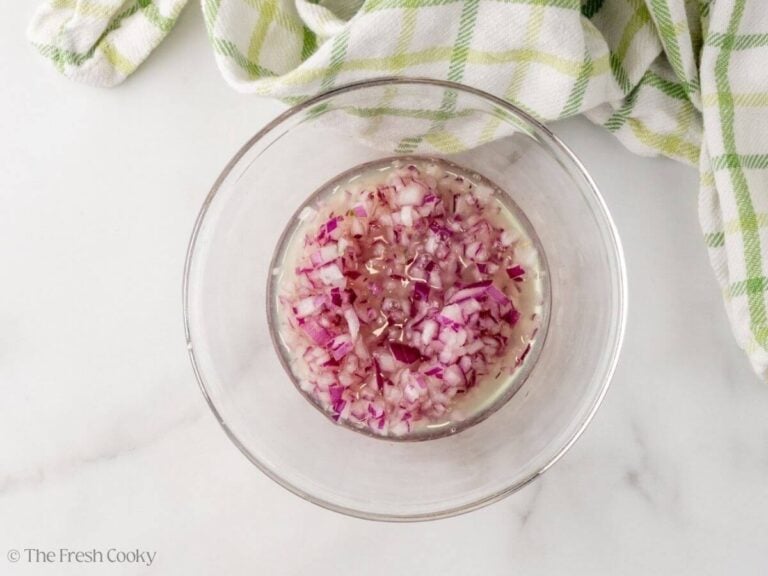 Diced red onions in lemon and lime juice in a bowl.