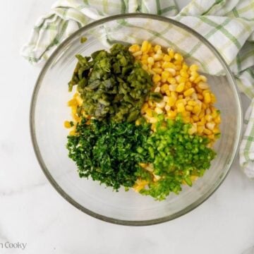Corn, poblano pepper, jalapeno pepper and cilantro in a large bowl.