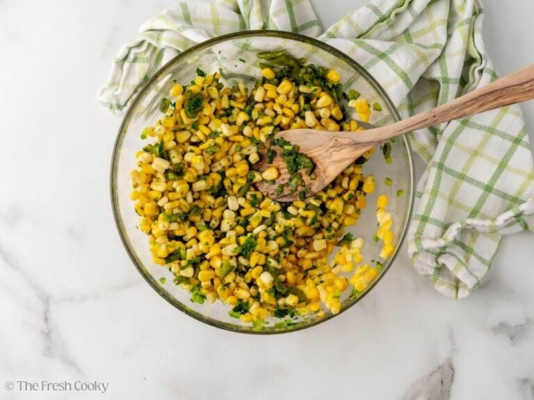 Corn mixed together with the peppers and cilantro in a bowl.