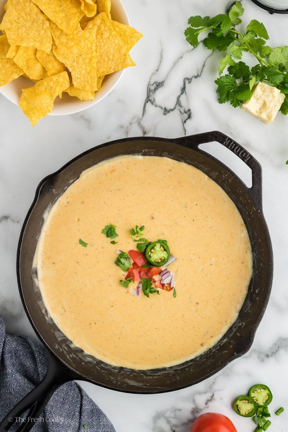 Ready to serve easy queso recipe without velveeta in cast iron pan with tortilla chips for dipping.