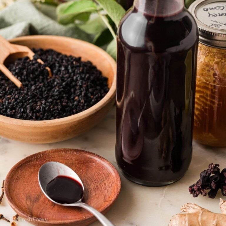 Elderberry syrup in bottle and a serving on a spoon.