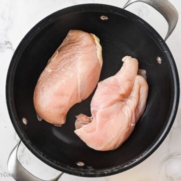 Two chicken breasts in a pot of water.