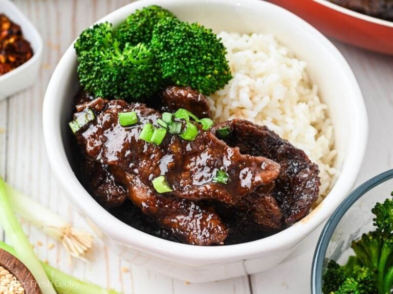 Mongolian beef slices in a bowl over white rice with steamed broccoli.
