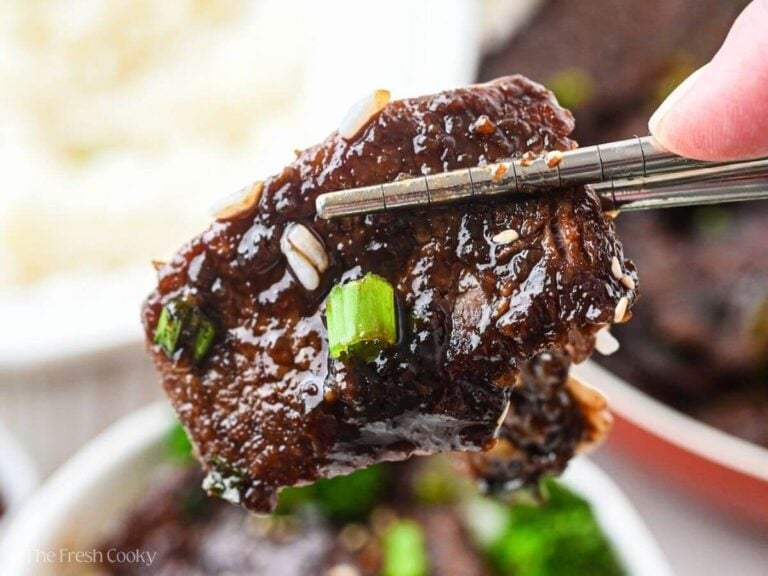 Chopsticks holding a sticky piece of mongolian beef.
