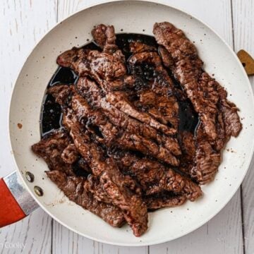 Returning the cooked beef to the pan.