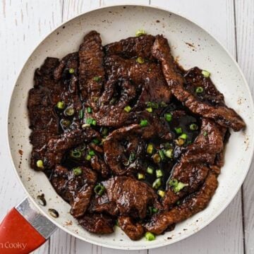 Mongolian beef in saucepan with sauce poured over.