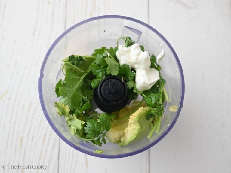 Avocado lime crema ingredients in food processor bowl.