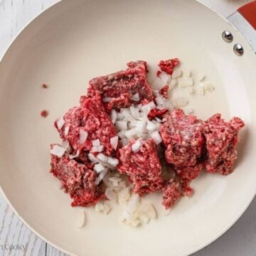 Ground beef and onions in skillet.